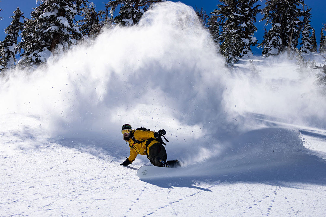 A snowboarder plows through fresh powder. 